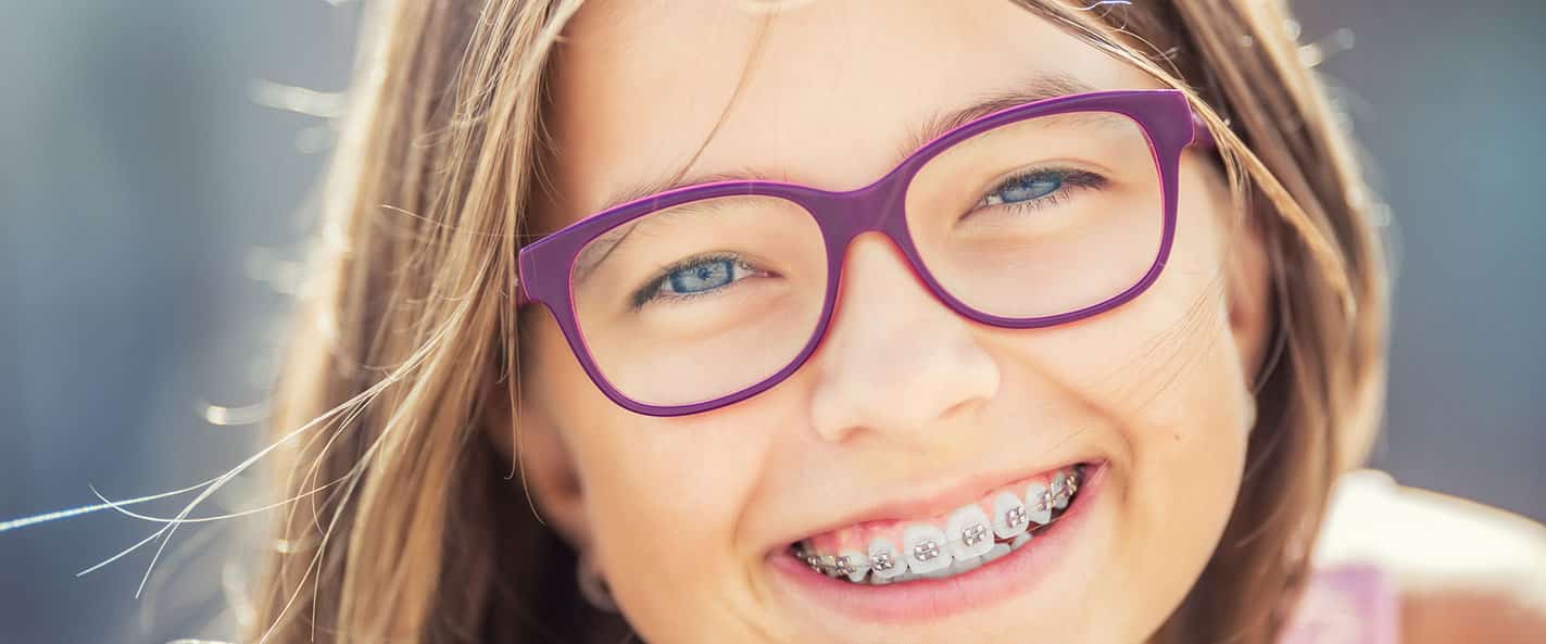 Girl with braces and glasses smiling