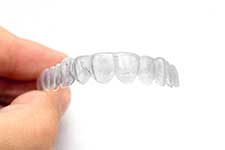A hand holding an Invisible Retainer.